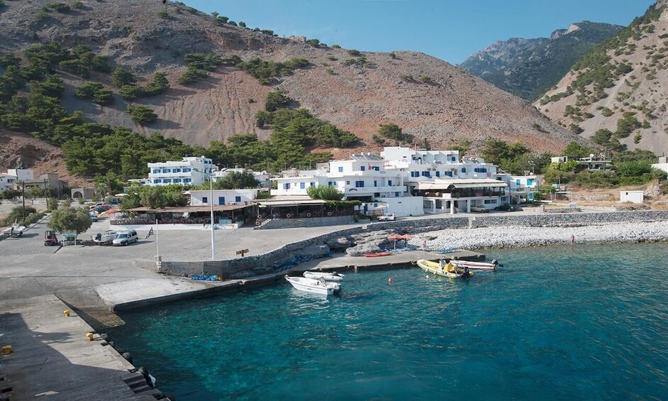 A coastal town with white buildings, a harbor, and mountains in the background. 2