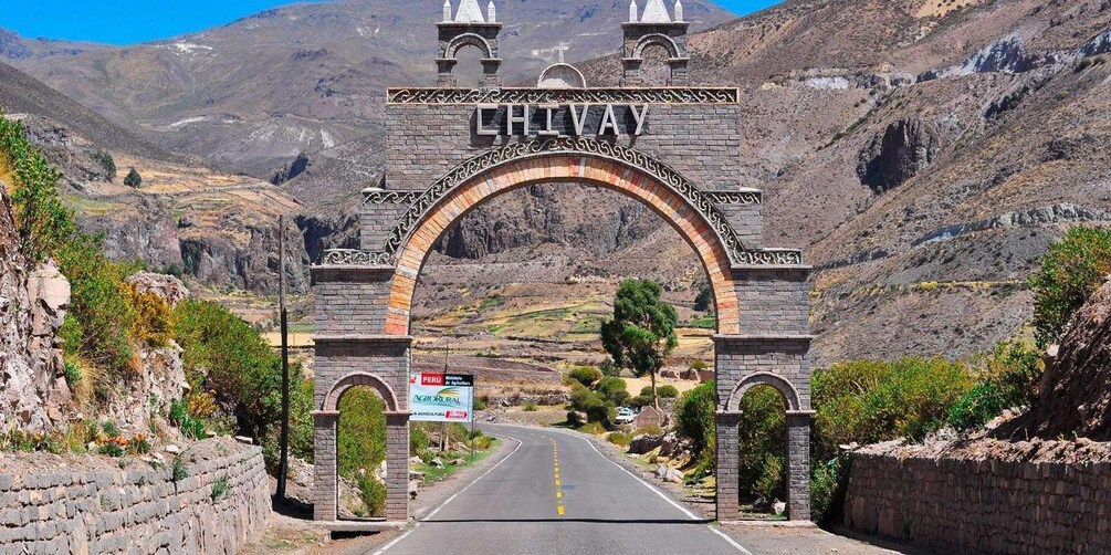 A stone archway with 'CHIVAY' inscribed at the top, leading to a road surrounded by mountainous terrain. 5