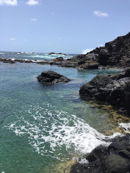 A rocky coastline with clear turquoise water and waves crashing against the rocks. 2