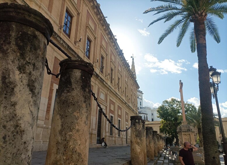 A historic building with columns, palm trees, and a clear sky. 4