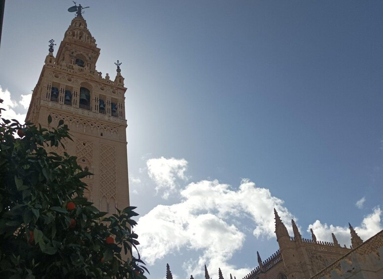 A tall tower with intricate architectural details and a clear blue sky with clouds. 2