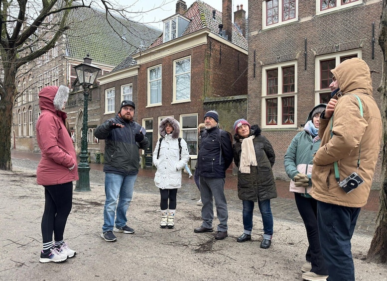 A group of people standing outdoors in a historic area with brick buildings and a cobblestone street. 1