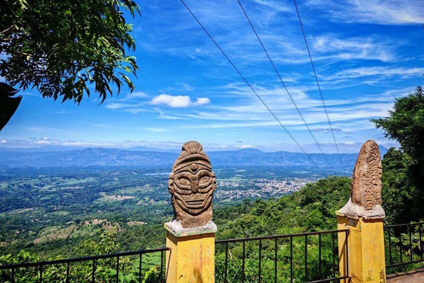 Un belvédère offrant une vue panoramique, agrémenté de deux statues de lions en pierre, d’une rambarde jaune, et donnant sur une vallée et des montagnes lointaines. 5