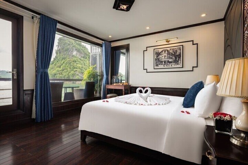 A hotel room with a large bed, a desk, a view of the outdoors, and a framed picture on the wall. 2