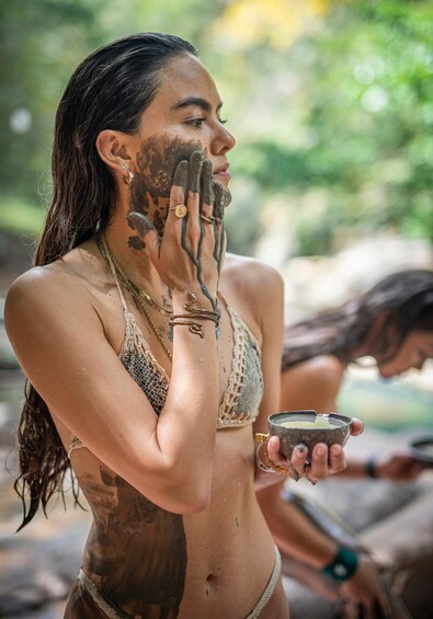 A person with mud on their face and body, holding a bowl. 4