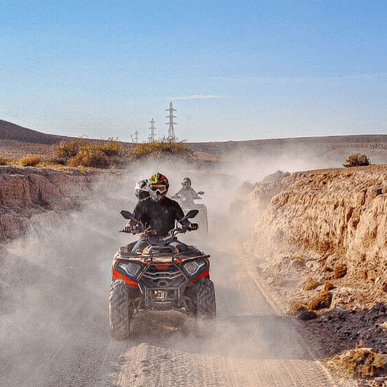 Two ATVs on a dusty road with a clear sky. 3