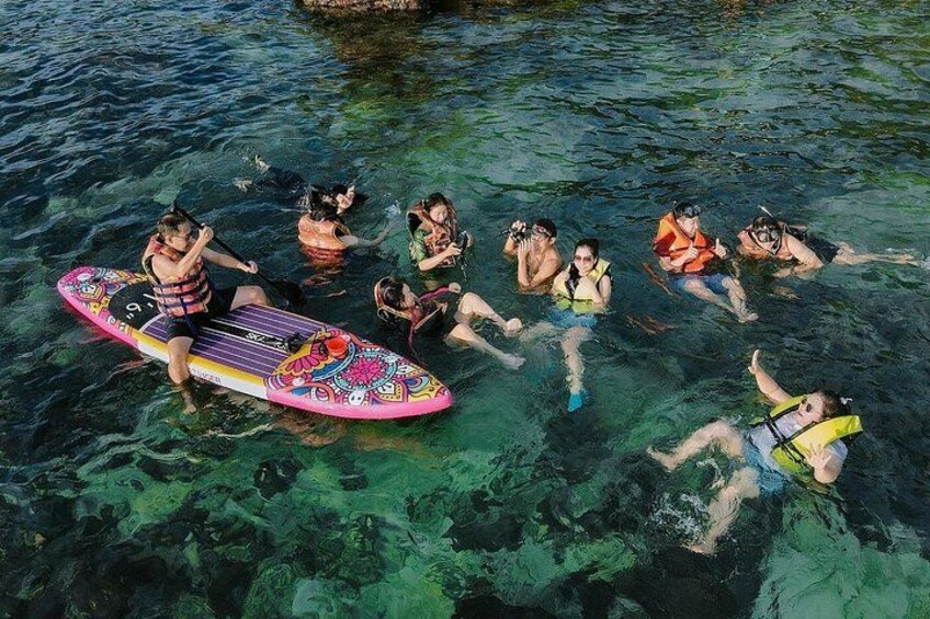 Des personnes flottant sur une étendue d’eau, tenant une planche de surf aux couleurs vives. 3