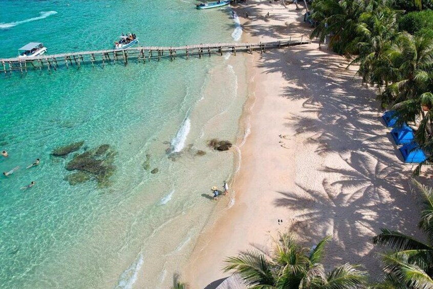 Une plage à l’eau turquoise et limpide, une jetée en bois et des palmiers. 2
