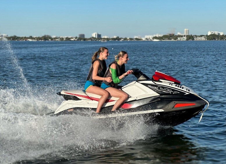 Two people jet skiing on a lake with a city skyline in the background. 5