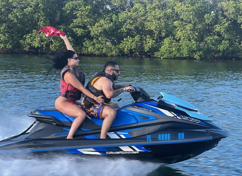 Two people on a jet ski with a water body and trees in the background. 3