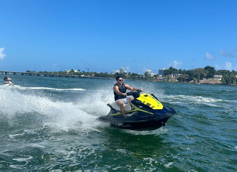 A person riding a jet ski on a body of water with a bridge and buildings in the background. 5