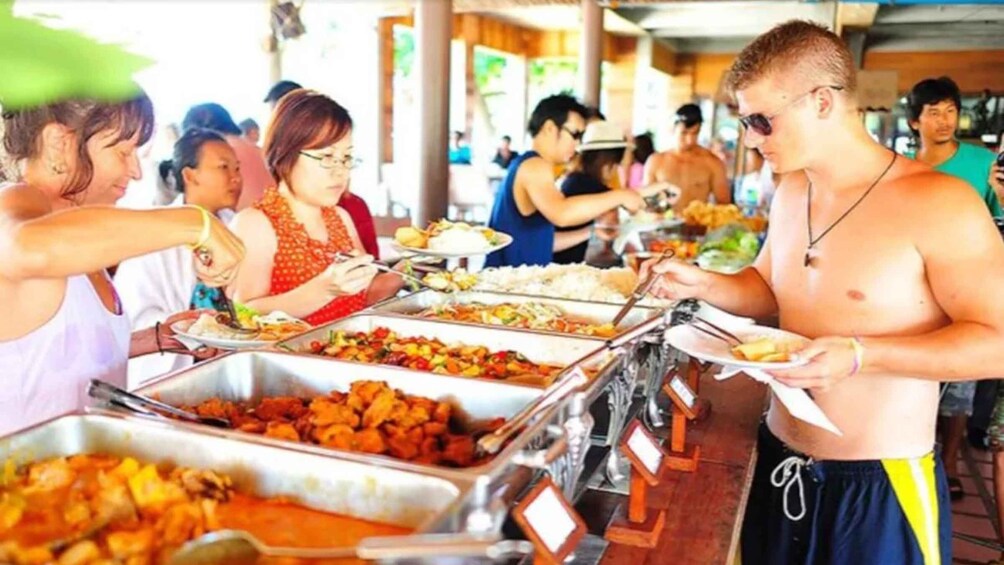 A buffet with various dishes and people serving themselves. 2