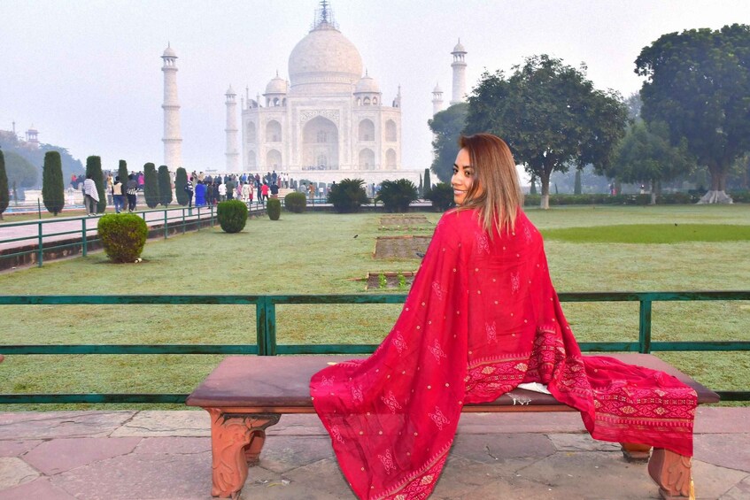 Henkilö istuu puistonpenkillä, ja taustalla näkyy Taj Mahal. 1