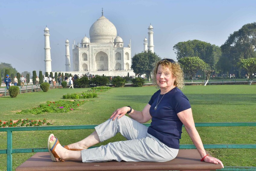 Henkilö istuu puistonpenkillä, ja taustalla näkyy Taj Mahal. 3