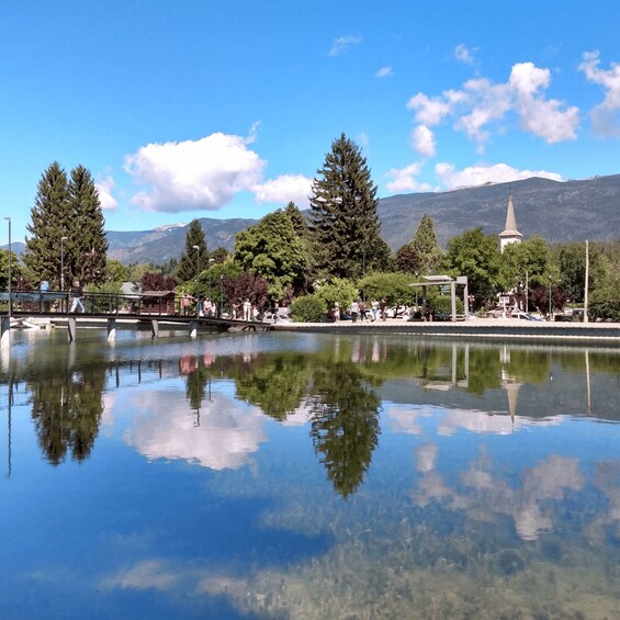A calm lake reflecting trees and a mountain range. 1