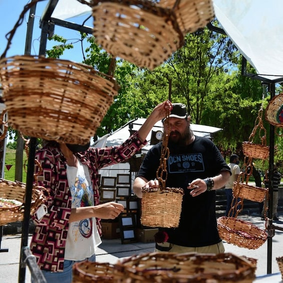 A person holding a basket at a market stall with wicker baskets hanging above. 5
