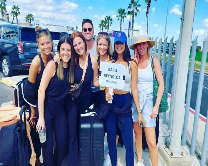 A group of people standing by a fence with a sign that reads "KARLI REYNOLDS WELCOME". 3