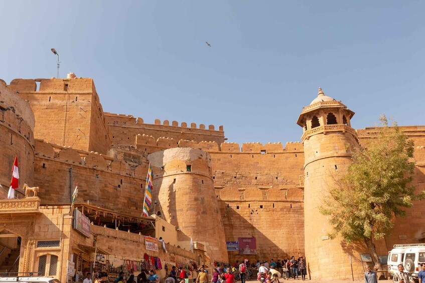A historic fort with large stone walls, a central tower, and a flagpole with multiple flags. 2