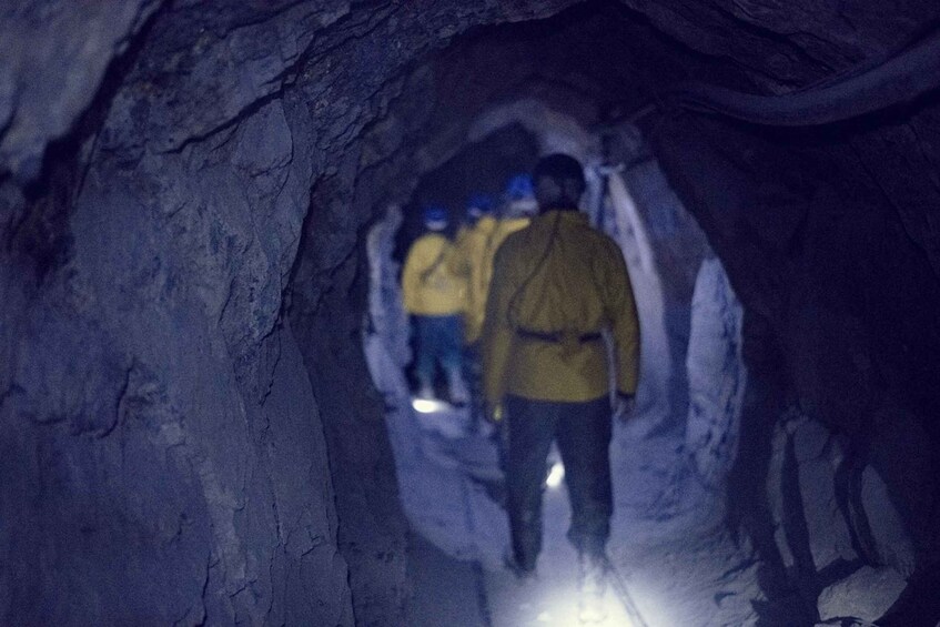 A group of people walking through a narrow, rocky tunnel. 1