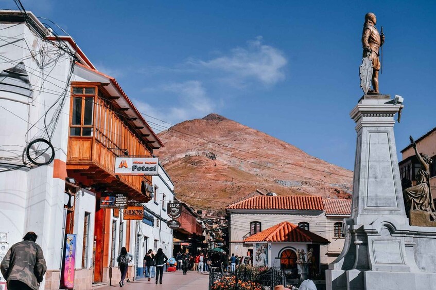 A street with shops, a mountain in the background, and a statue. 4