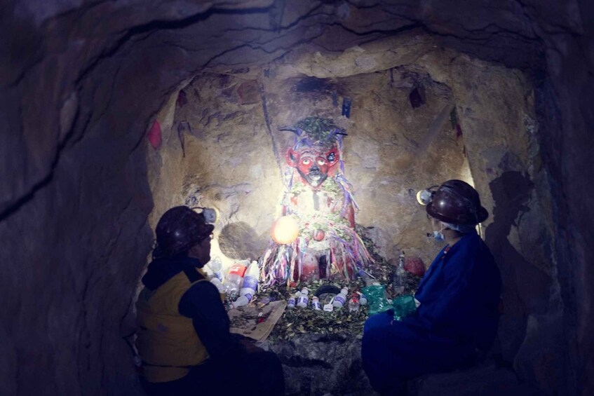 A cave with a colorful statue and various items scattered around. 2