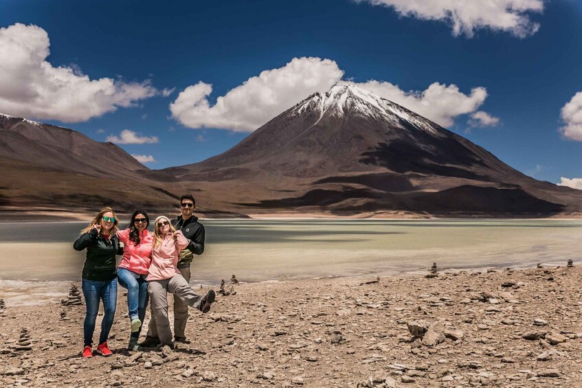 A group of people posing in front of a snow-capped mountain and a calm lake. 4