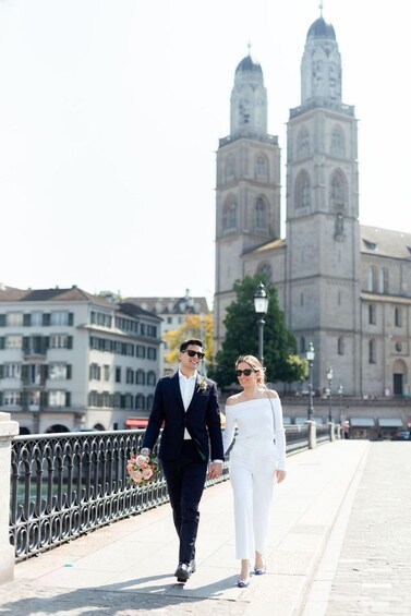 A couple walking on a bridge with a historic building in the background. 4