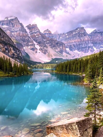 A clear mountain lake surrounded by dense forests and rugged peaks. 3
