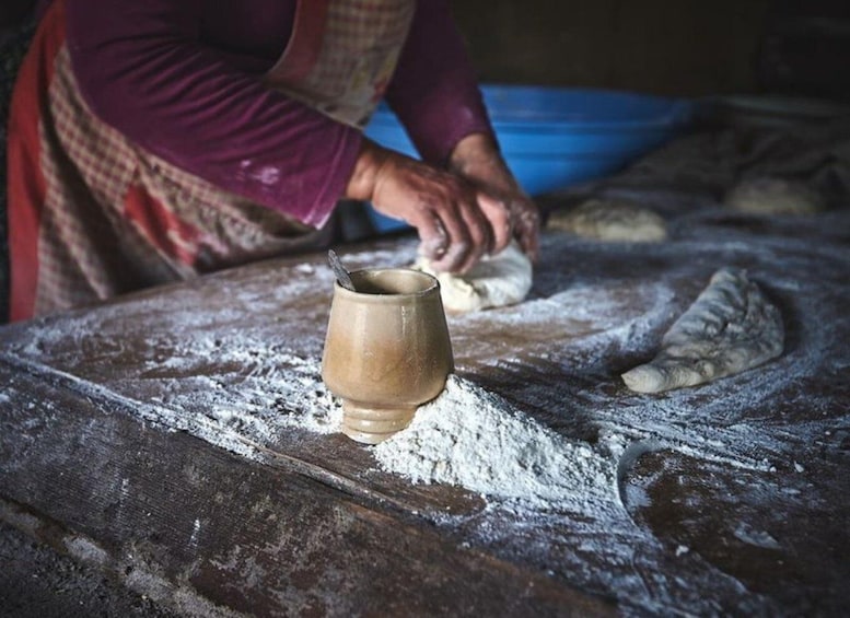 A person kneading dough on a flour-dusted wooden surface. 1