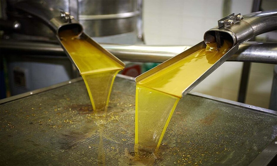 Un embudo metálico vertiendo un líquido amarillo sobre una superficie de malla. 2