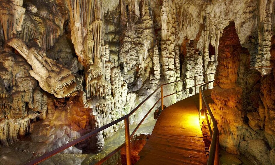 Una cueva con estalactitas y estalagmitas, un pasillo de madera y una barandilla de metal. 3