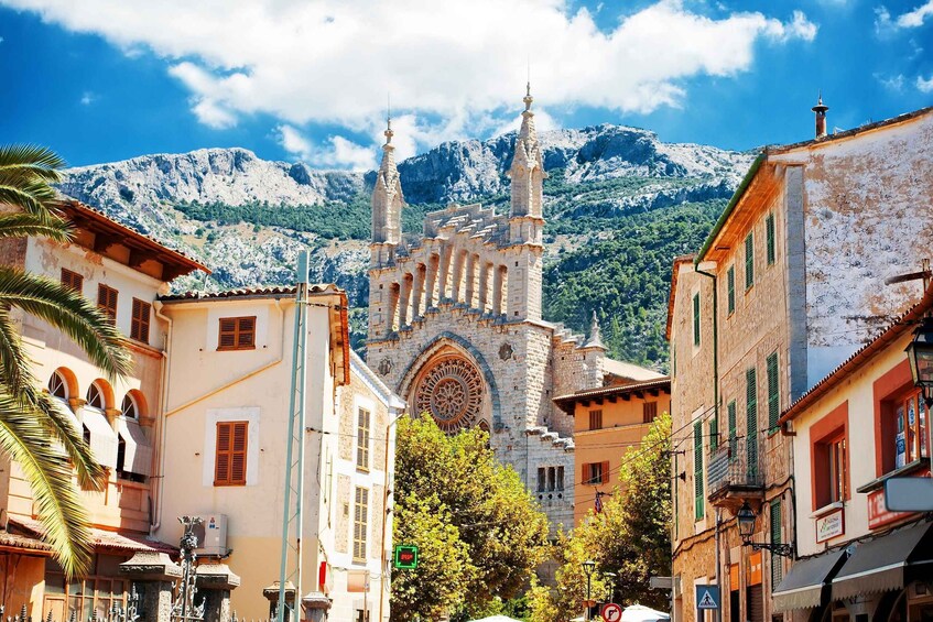 A historic church with two towers, a mountain in the background, and surrounding buildings. 2