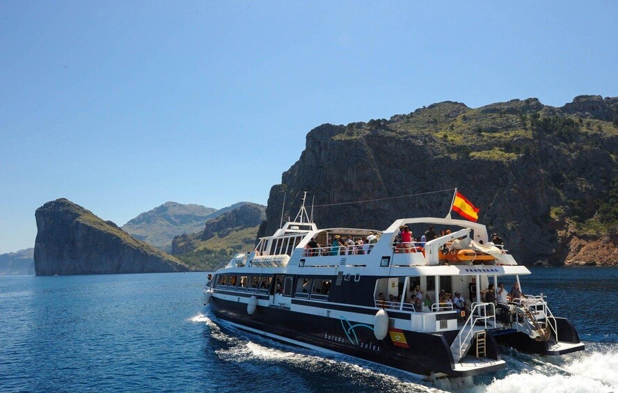 A boat named 'PANDORA' with passengers, sailing near rocky cliffs. 1
