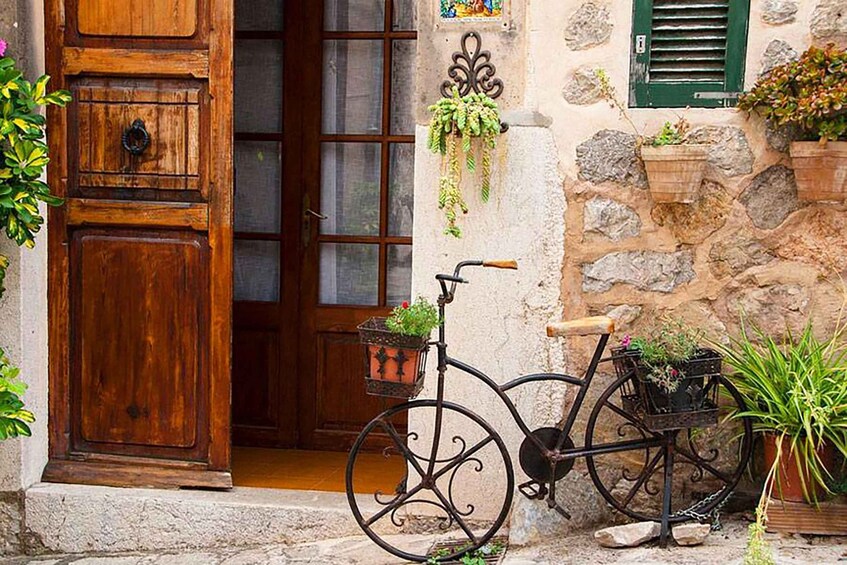 A rustic wooden door, a vintage bicycle with baskets, and potted plants against a stone wall. 4