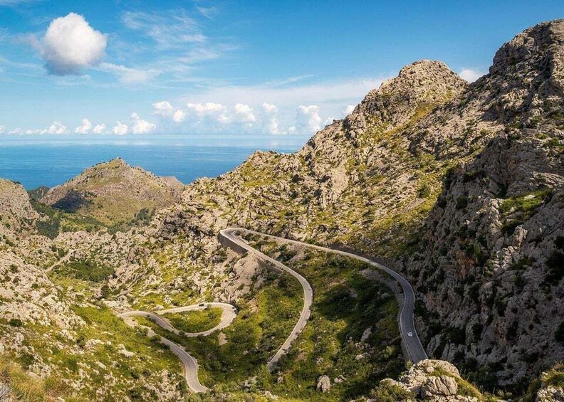 A winding mountain road with rocky terrain and sparse vegetation. 5