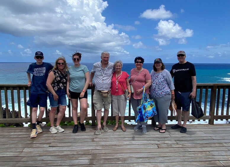 A group of people standing on a wooden deck by the ocean. 2