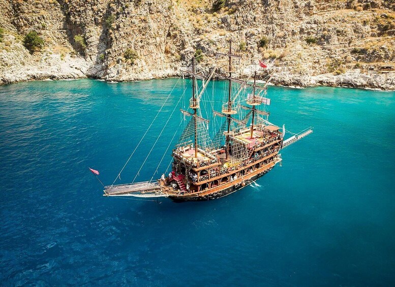 A large wooden ship with multiple masts sailing on turquoise waters. 3