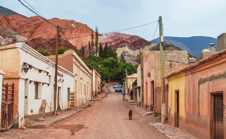 A narrow street flanked by buildings with a mountainous backdrop. 5