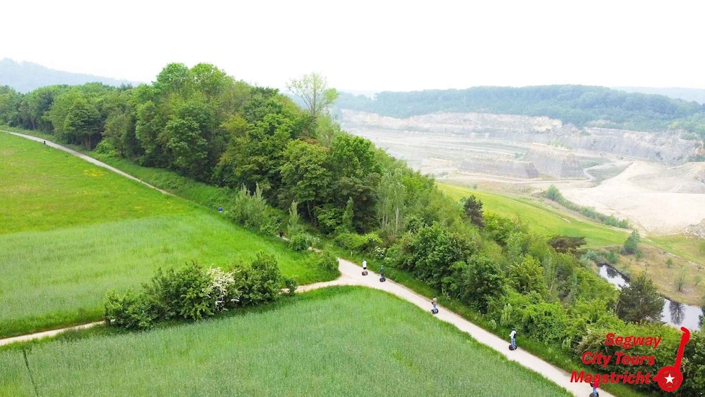 A scenic view of Segway tours in Maastricht, featuring lush green fields, a winding path, and a river. 2