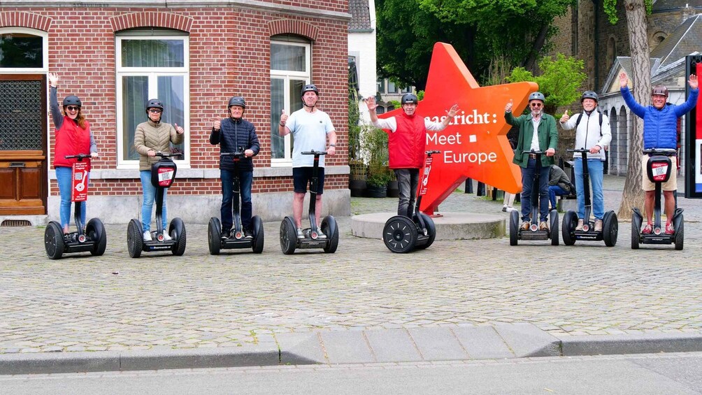 People riding Segways on a cobblestone street with a large red star sign in the background. 1
