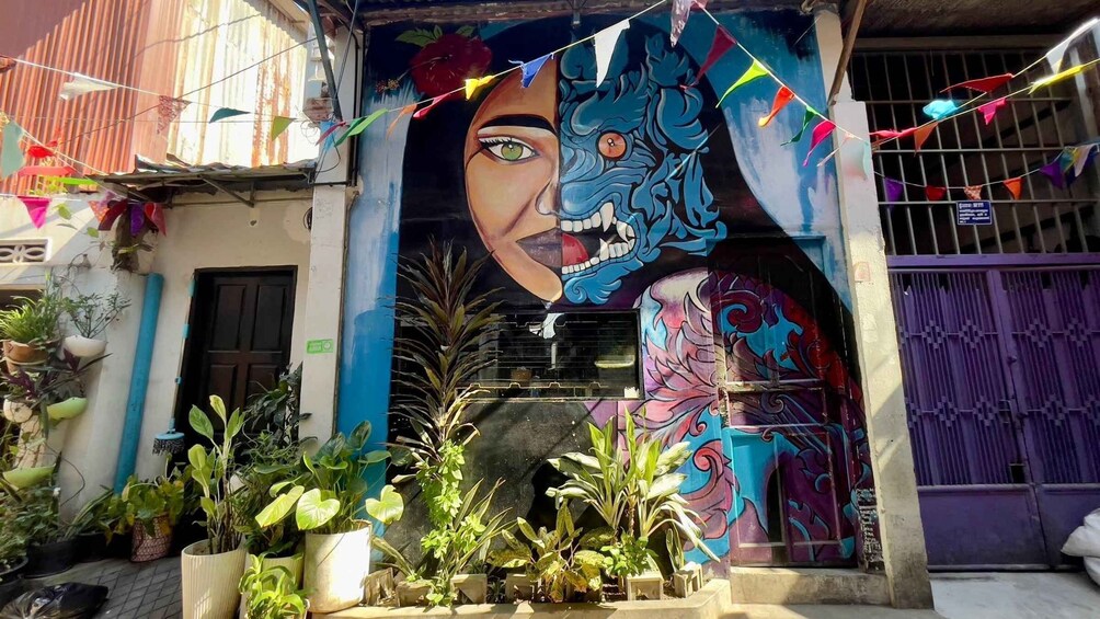 A building with a colorful mural, potted plants, and a purple gate. 2