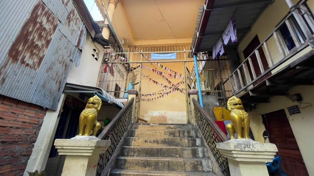 A staircase with golden lion statues at the base, leading to a building with a corrugated metal exterior and a blue banner. 5