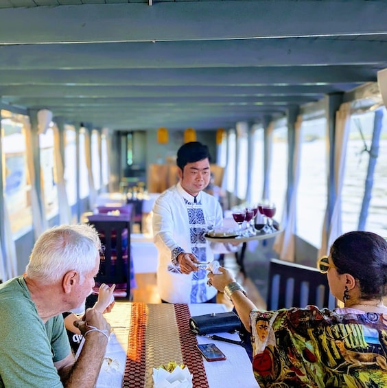 A dining area on a boat with a waiter serving drinks. 4