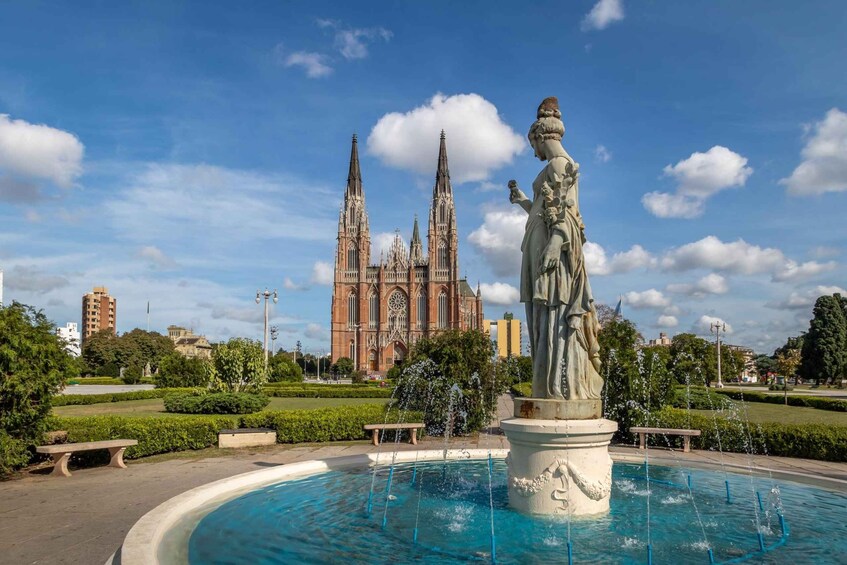 Una fuente con una estatua en primer plano y una catedral al fondo. 5