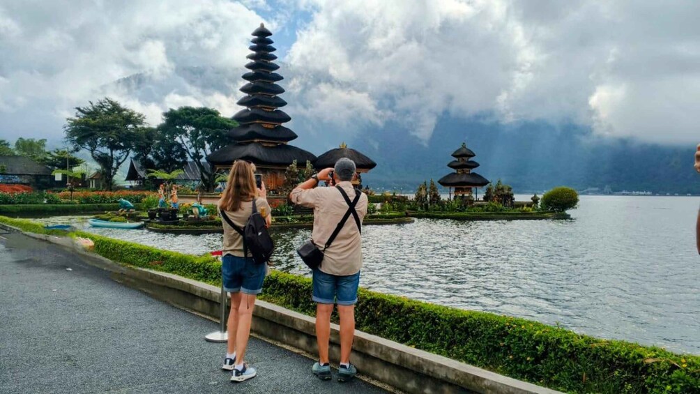 A couple taking a photo of a pagoda by a lake. 4