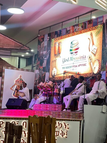 A stage with musicians performing, a banner with 'Yod Abyssinia' text, and traditional instruments. 4