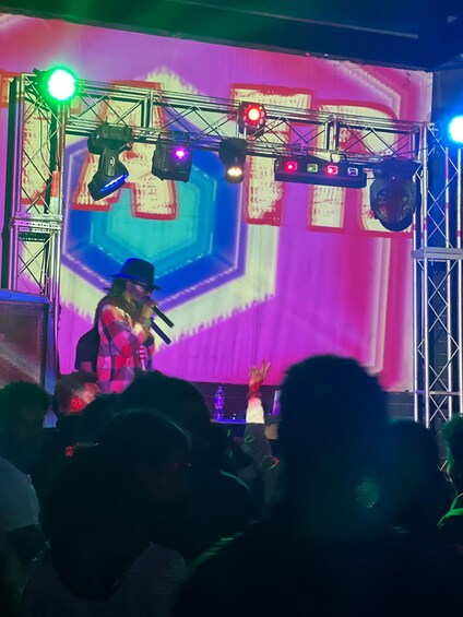 A stage with colorful lights and a DJ performing. 3
