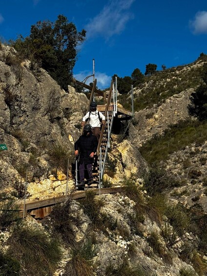 A person climbing a wooden staircase on a rocky hillside. 2