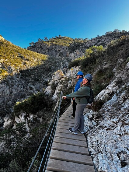 Two hikers on a wooden bridge in a rocky mountainous area. 4