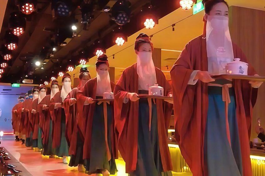 A line of performers in traditional costumes carrying trays. 2